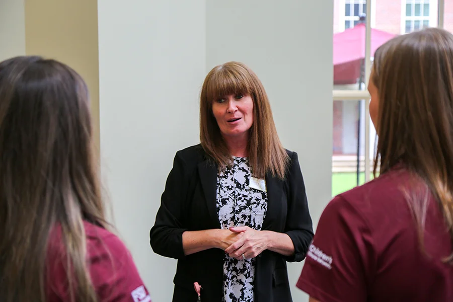 Pauline Hoffman of the Van Durme PrimaryHealth Center talks with two Dance Marathon at FSU student leaders in maroon shirts.